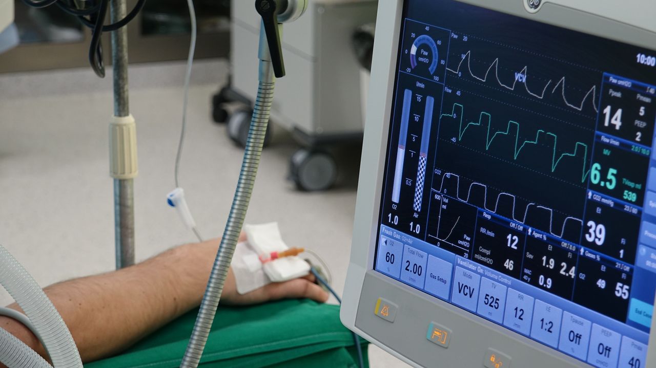 services-01 A close-up of a patient's hand connected to medical equipment in an ICU room.