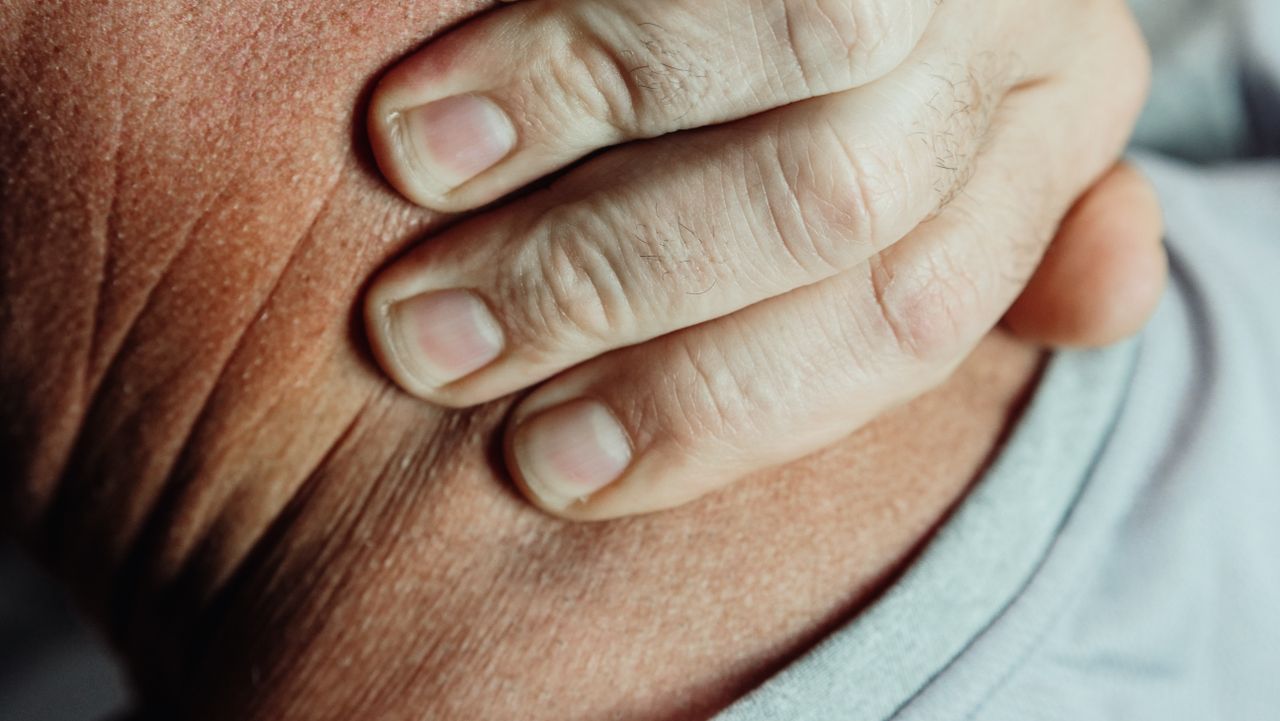 services-04 A detailed close-up of a person's hand touching their neck, suggesting pain or discomfort.