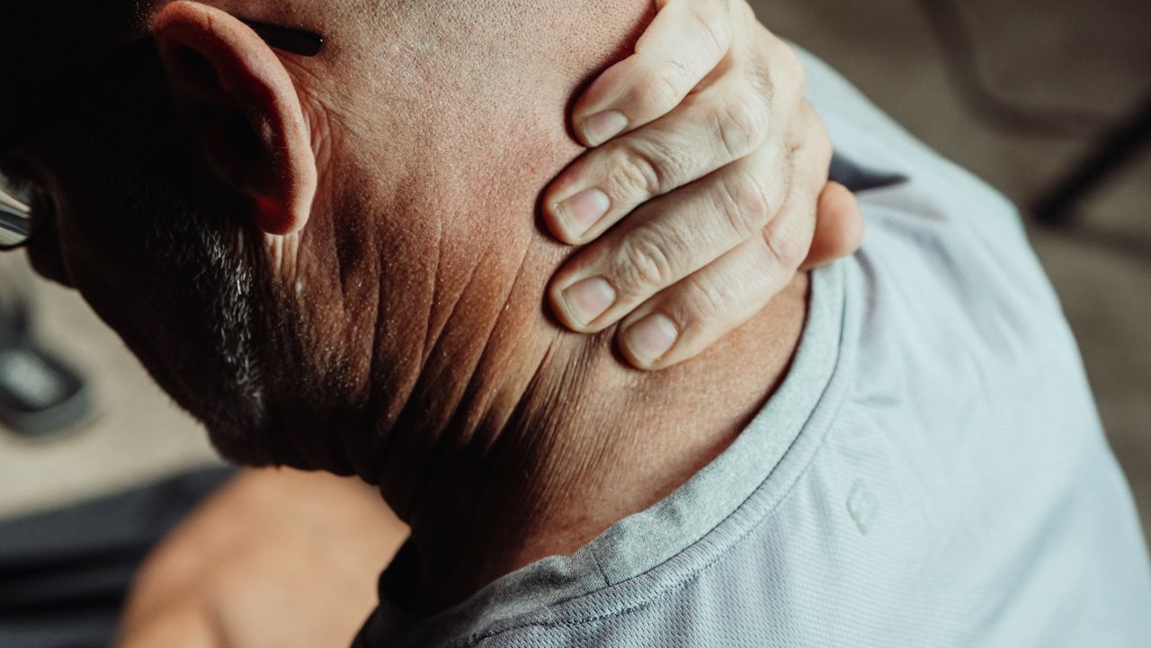 services-03 Man with neck pain holding his neck in discomfort, conveying tension or stress.
